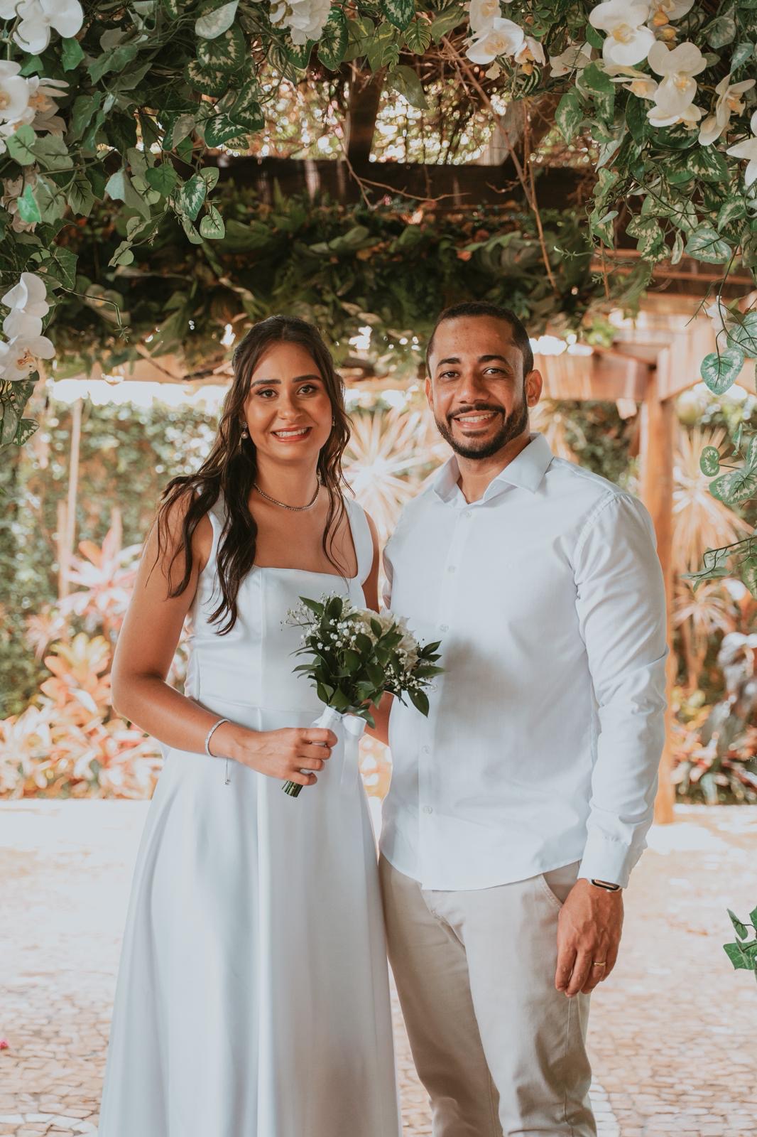 Juliana e Marcos sob o arco de flores